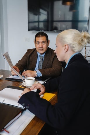 business man and woman sitting around a conference table discussing safety practices